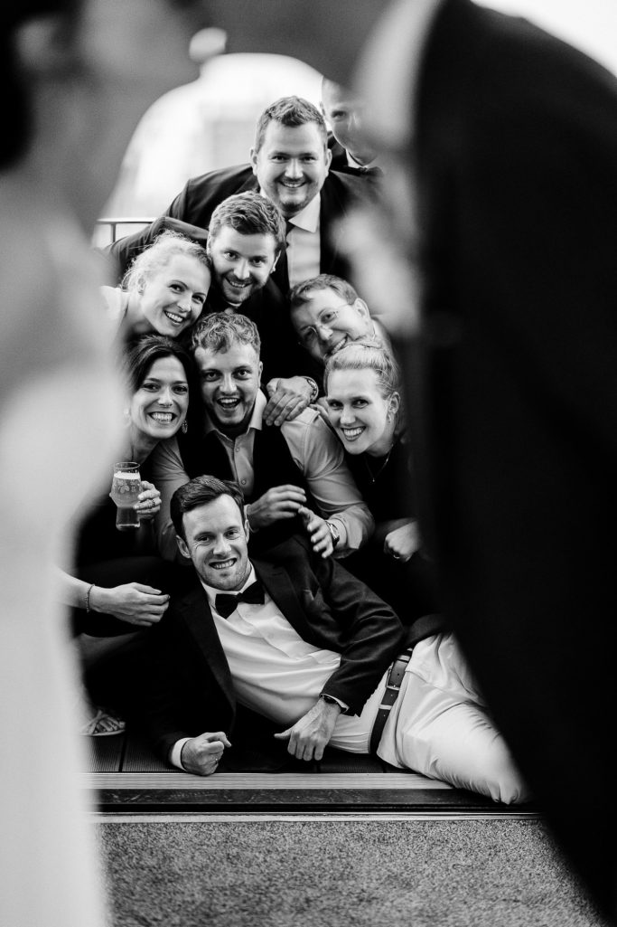 Braut und Bräutigam posieren mit einer Gruppe von fröhlichen Gästen.