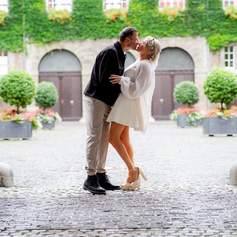 Paar küsst sich romantisch in einer malerischen Umgebung mit Pflanzen.