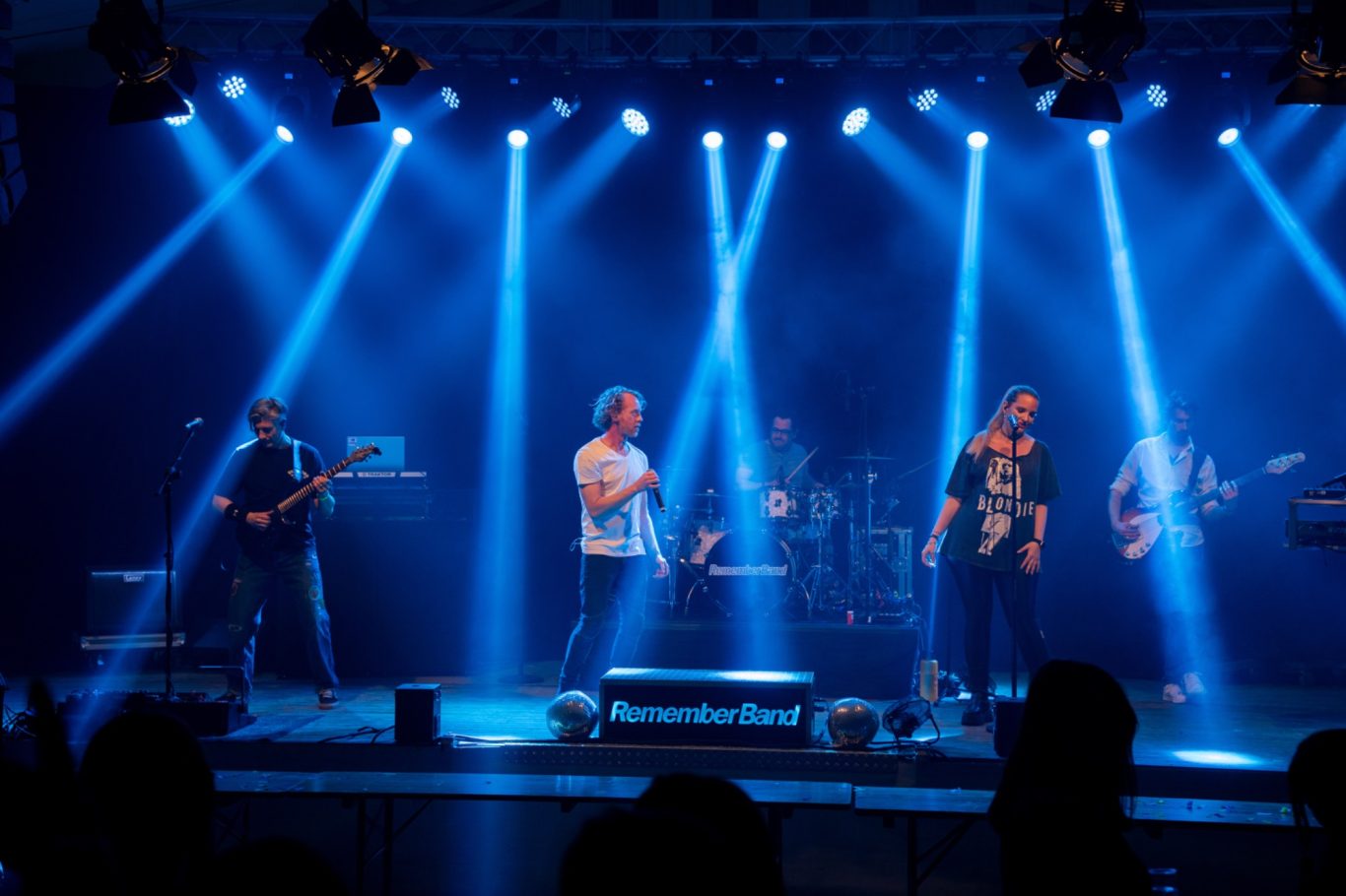 Eine Band tritt auf einer Bühne mit blauen Lichtern auf.