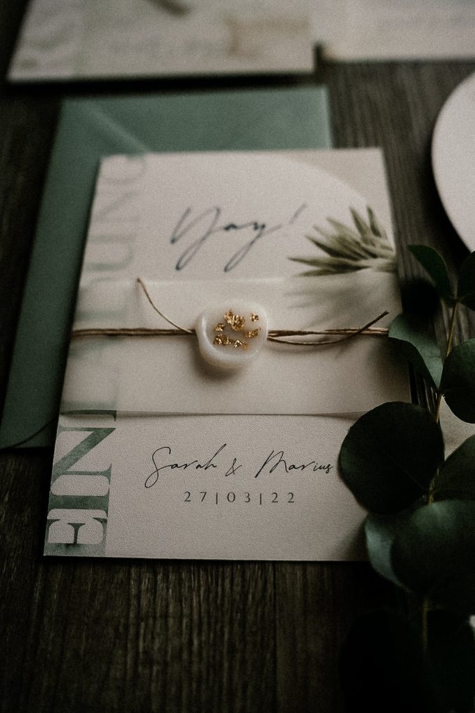 Ein elegantes Einladungskärtchen mit Blumendekor und einer grünen Umschlag.