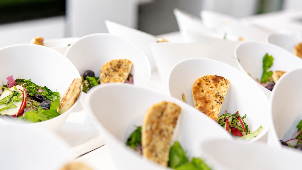Frischer Salat mit gemischtem Gemüse und knusprigem Brot in weißen Schalen serviert.