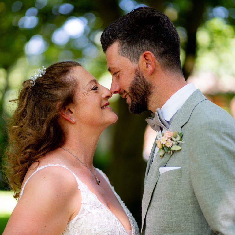 Liebespaar steht sich gegenüber, lächelt strahlend in der Natur.