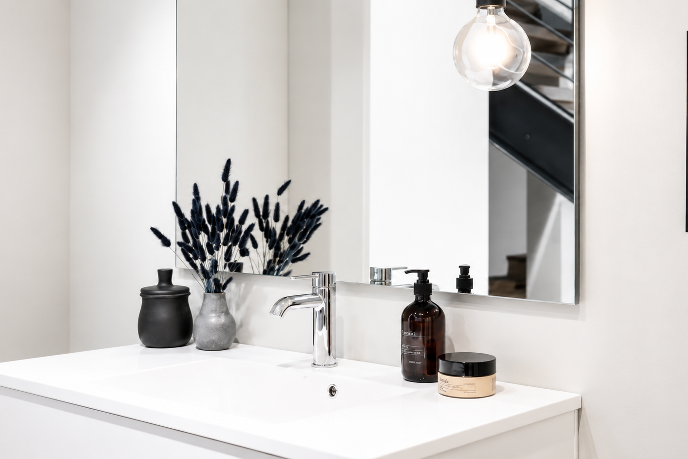 Modernes Badezimmer mit Waschtisch, Spiegel, dekorativen Vasen und stilvoller Beleuchtung.