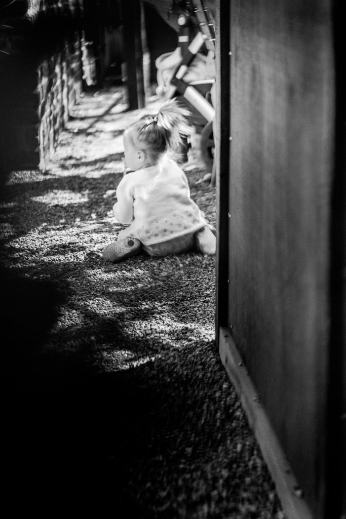 Ein Kleinkind krabbelt auf dem Boden, umgeben von Schatten und Natur.