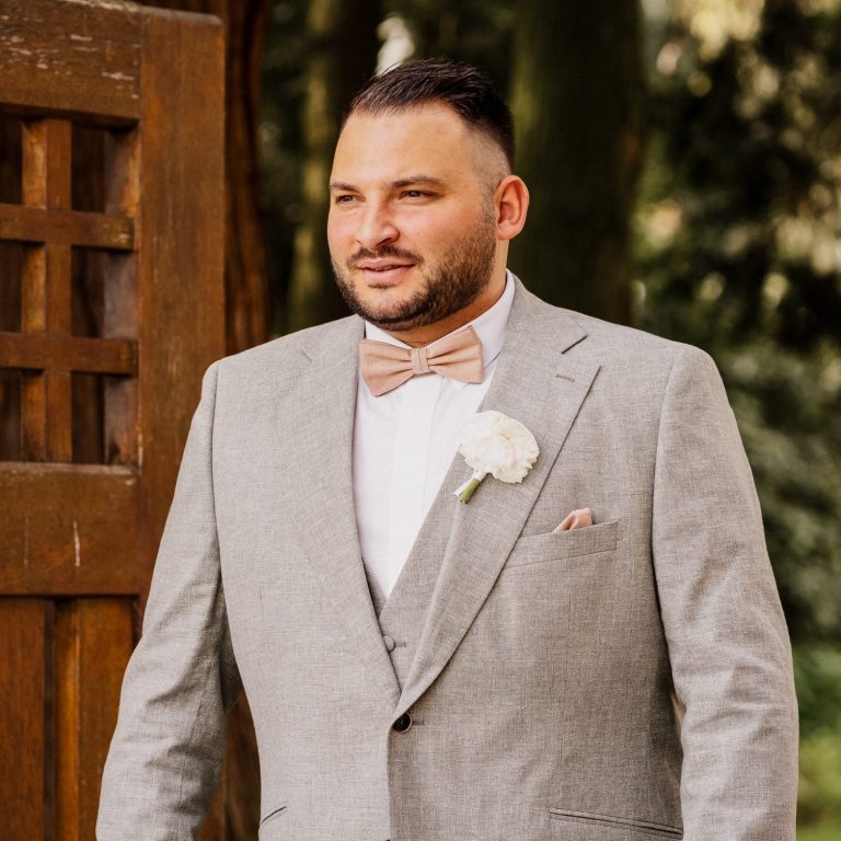 Zwei Frauen umarmen sich lächelnd vor einer Holztür, elegant gekleidet.