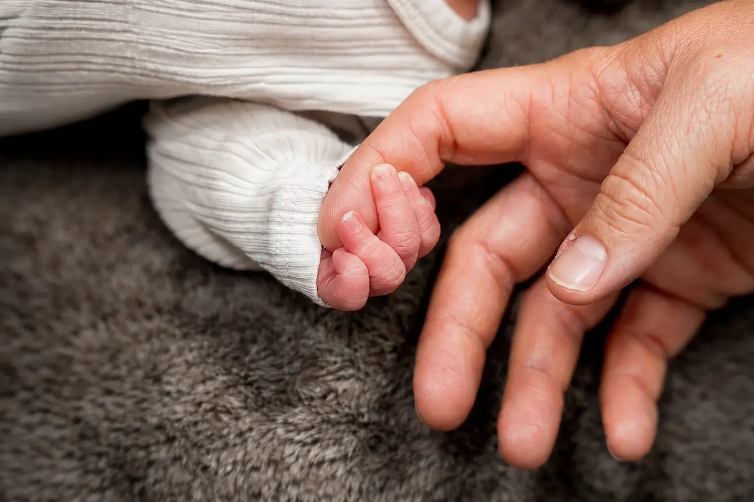 Babyhand hält den Finger eines Erwachsenen