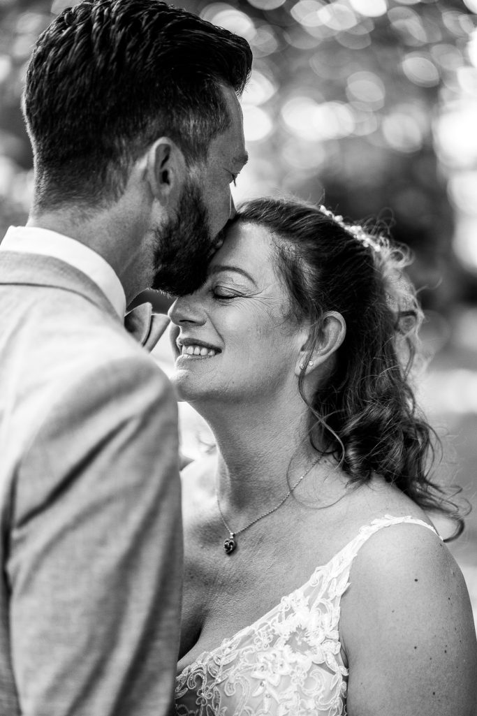 Ein Paar steht nah beieinander und lächelt, umgeben von unscharfem Hintergrund.