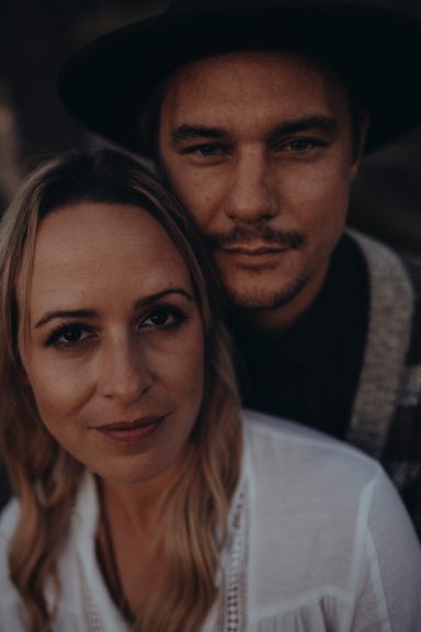 Ein Paar posiert eng umarmt, beide lächeln in die Kamera.