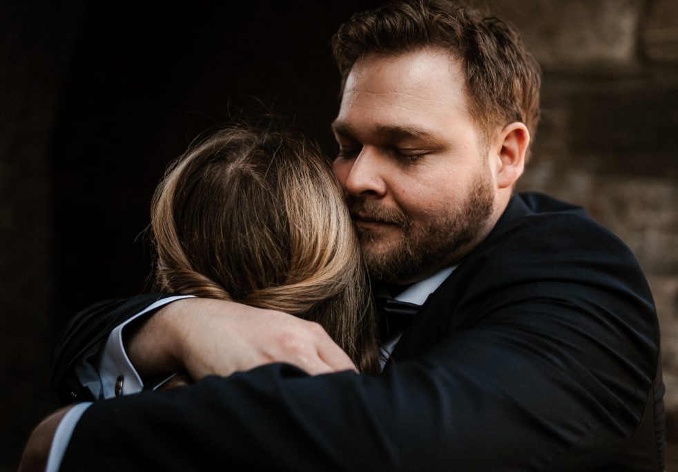 Ein Paar umarmt sich innig, beide mit lächelnden Gesichtern und festem Halt.
