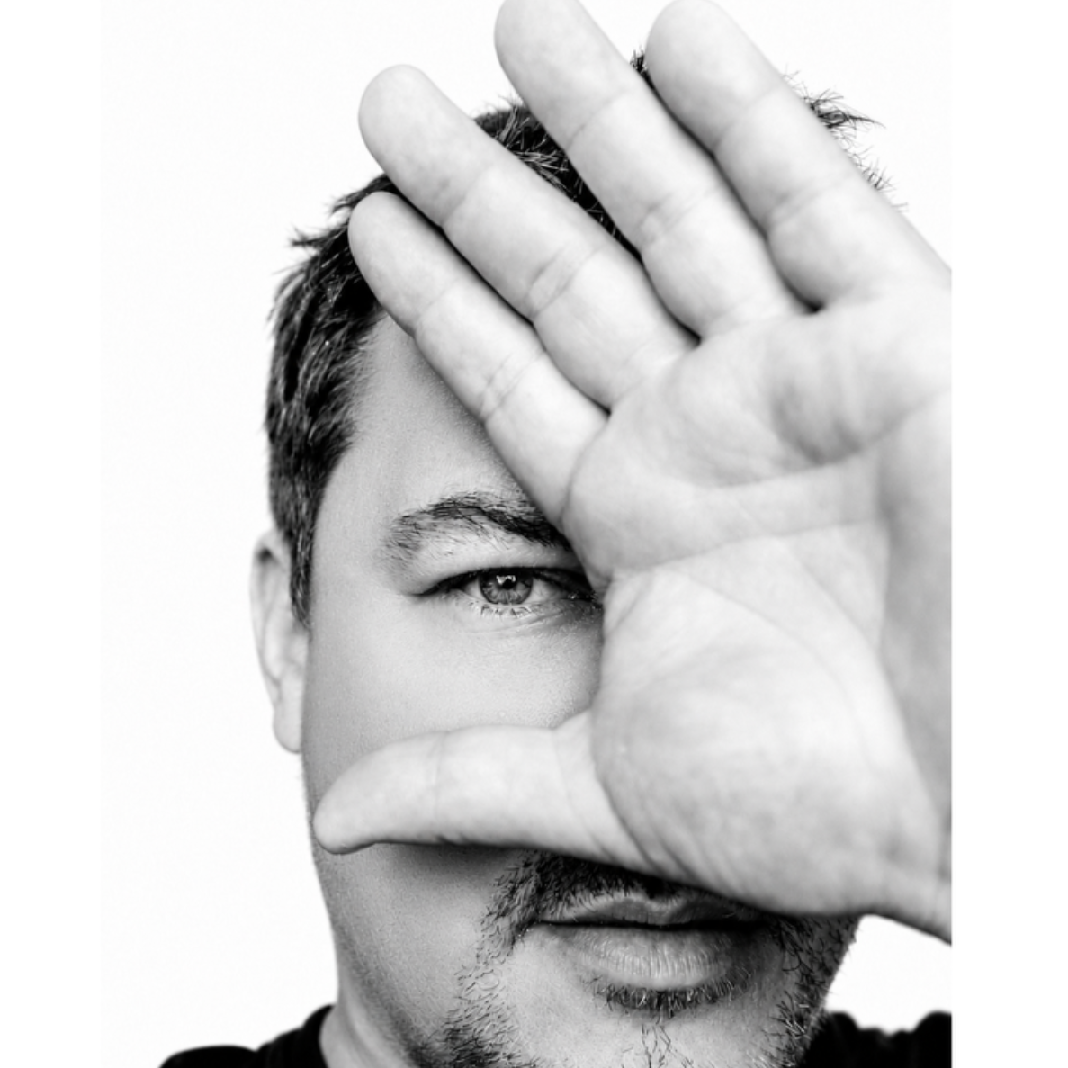 Ein Mann bedeckt sein Gesicht mit der Hand und schaut durch die Lücken.